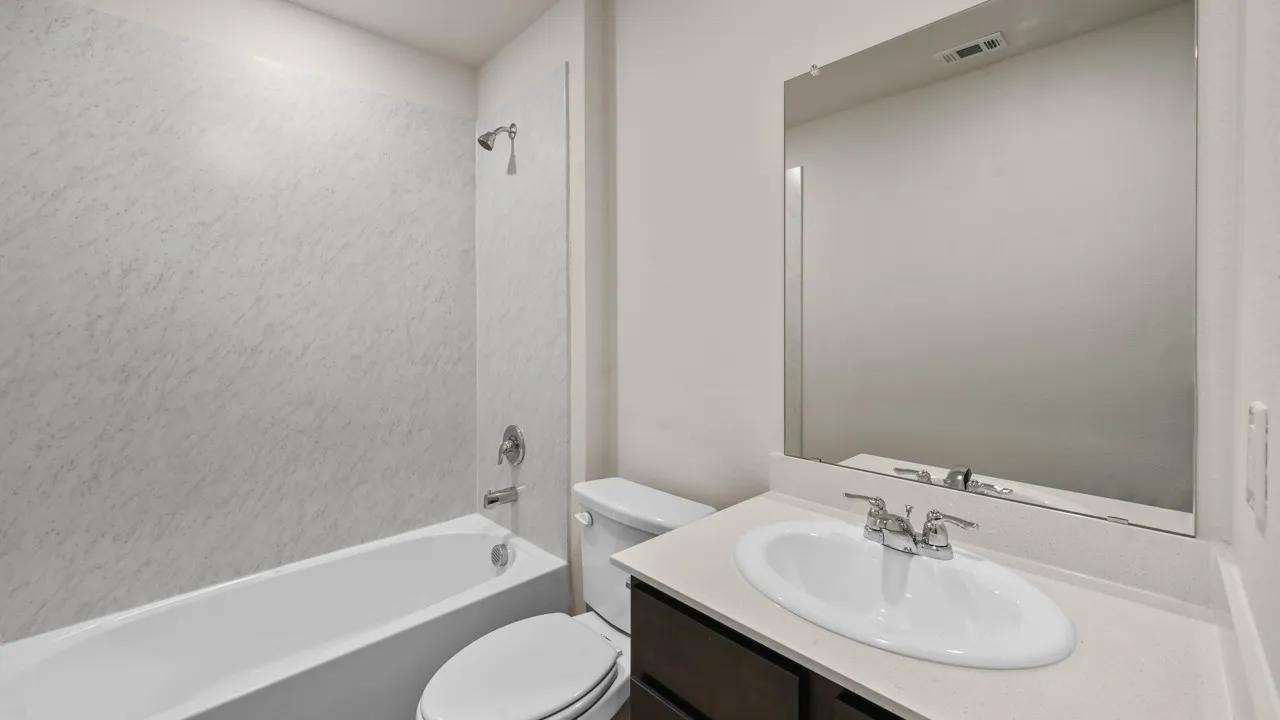 Bathroom featuring a white bathtub, shower with white textured surround, dark wood vanity with a light countertop, and a large wall-mounted mirror