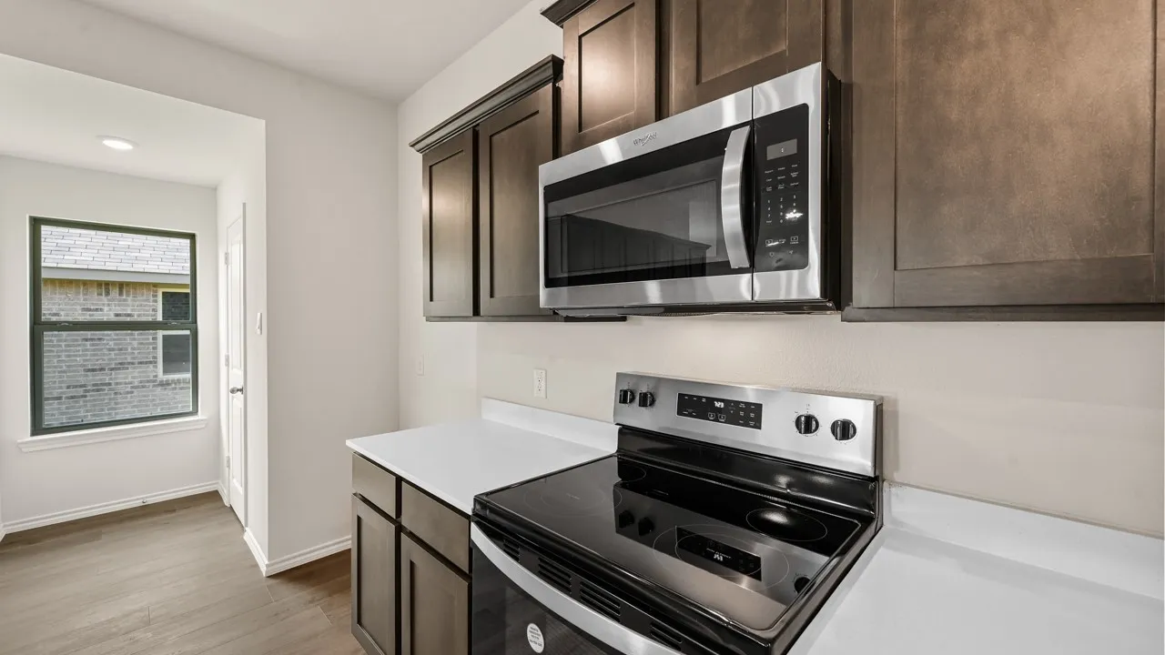Kitchen area featuring stainless steel appliances, dark wood cabinetry, and white countertops