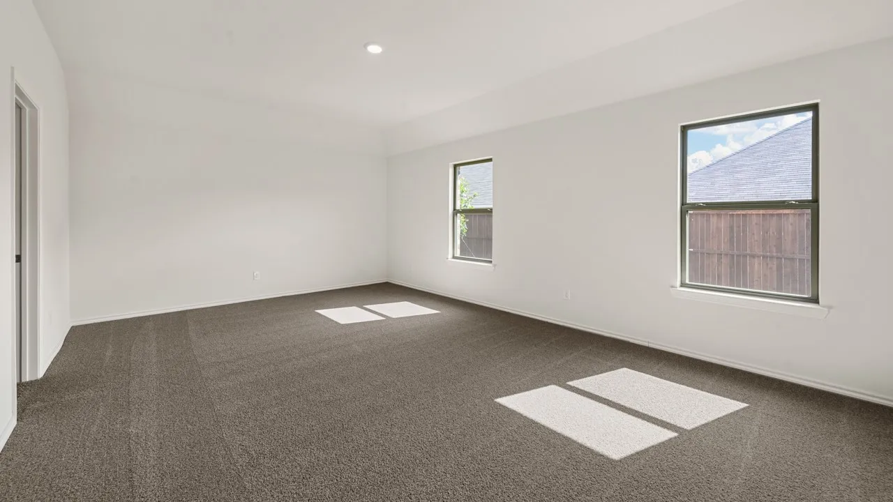 Spacious room featuring neutral carpeting, white walls, and multiple windows