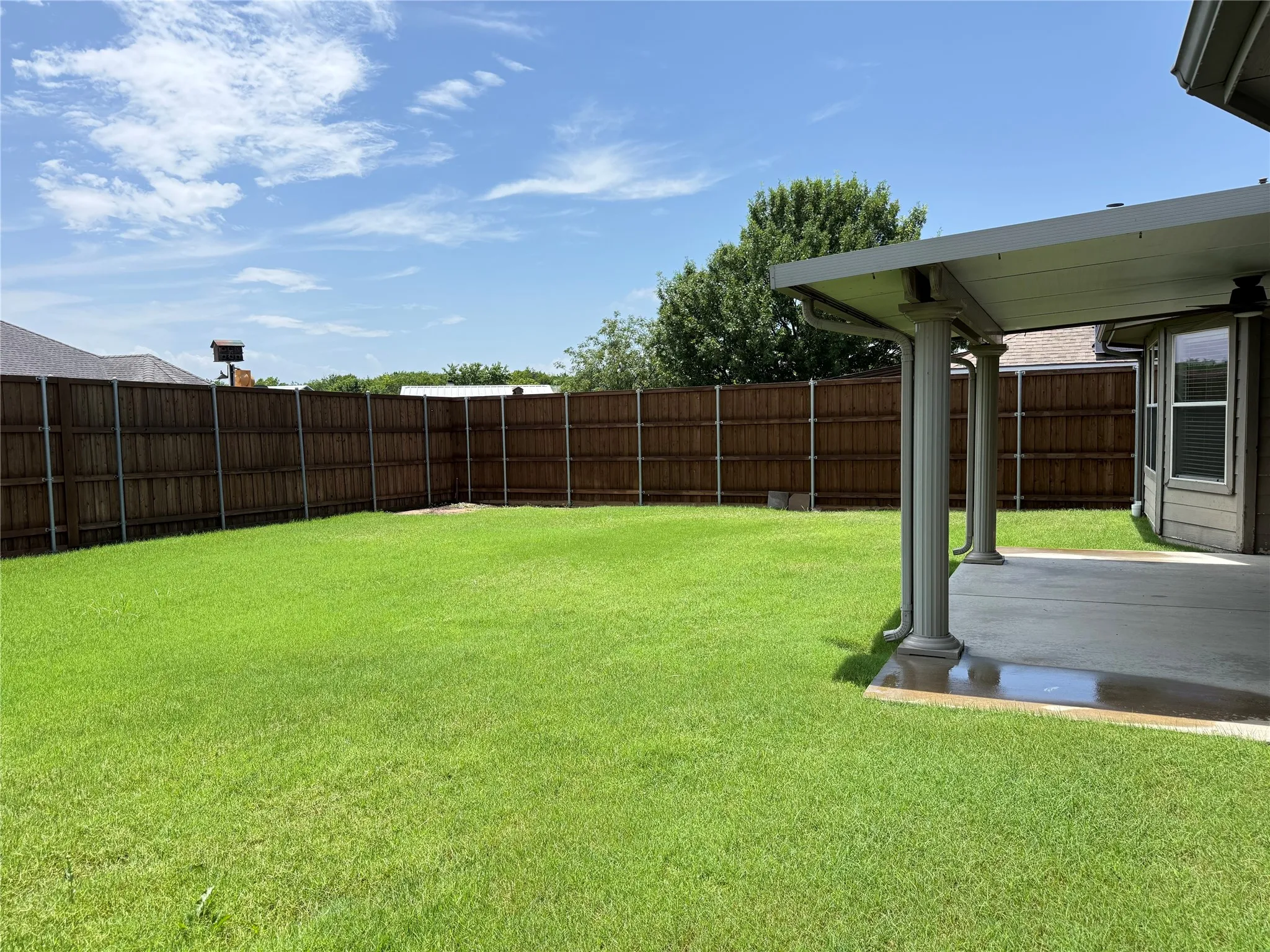 Fenced backyard with covered patio, lawn space, and room to relax, play, garden, or entertain.