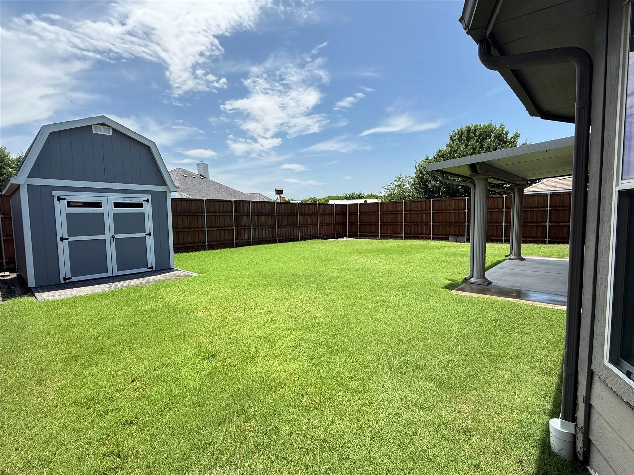 Backyard view with storage shed, privacy fencing, and open lawn space for everyday outdoor living.