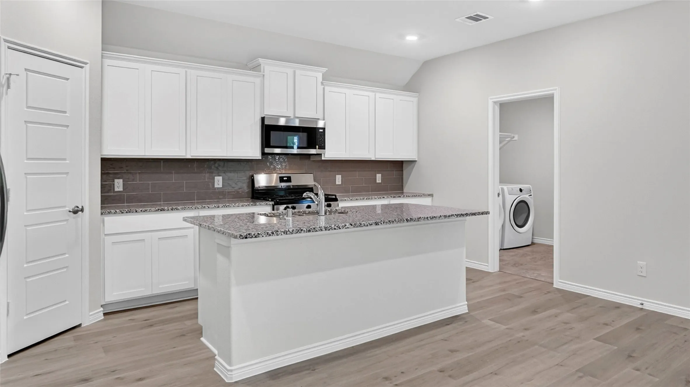 Kitchen featuring a central island, white cabinetry, granite countertops, and wood-finish flooring