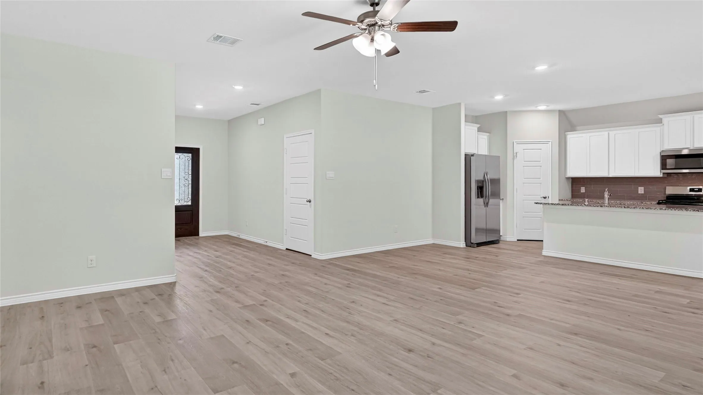 Open-concept living space featuring wood-finish flooring, recessed lighting, and a ceiling fan