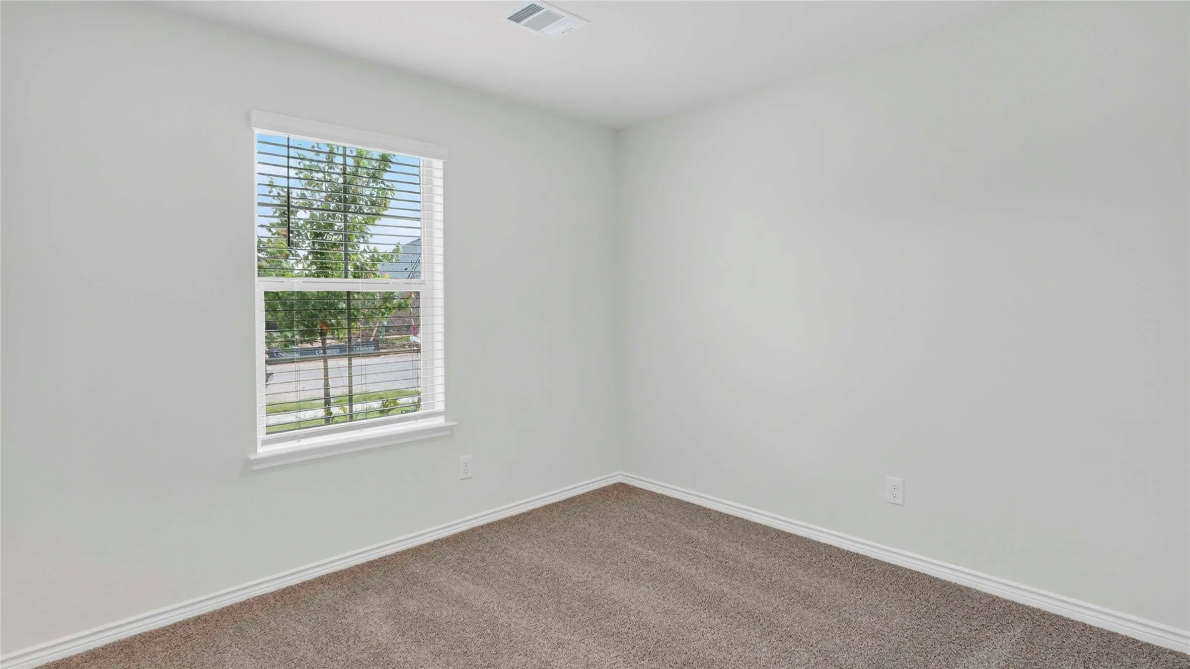 Room featuring neutral wall tones, window with horizontal blinds, tan carpet, and white trim