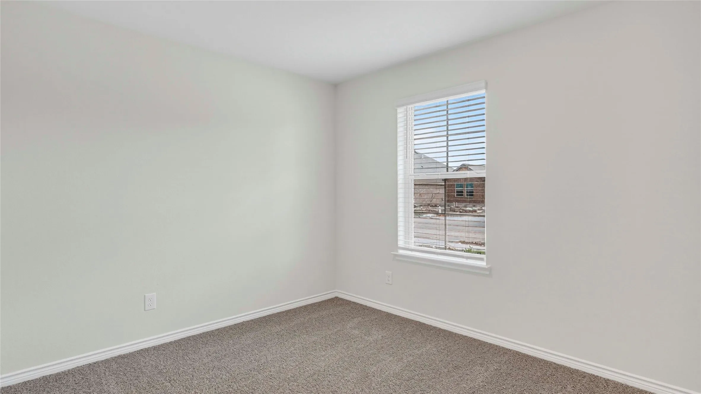 Carpeted interior space featuring light-colored walls, a window with horizontal blinds, and white trim