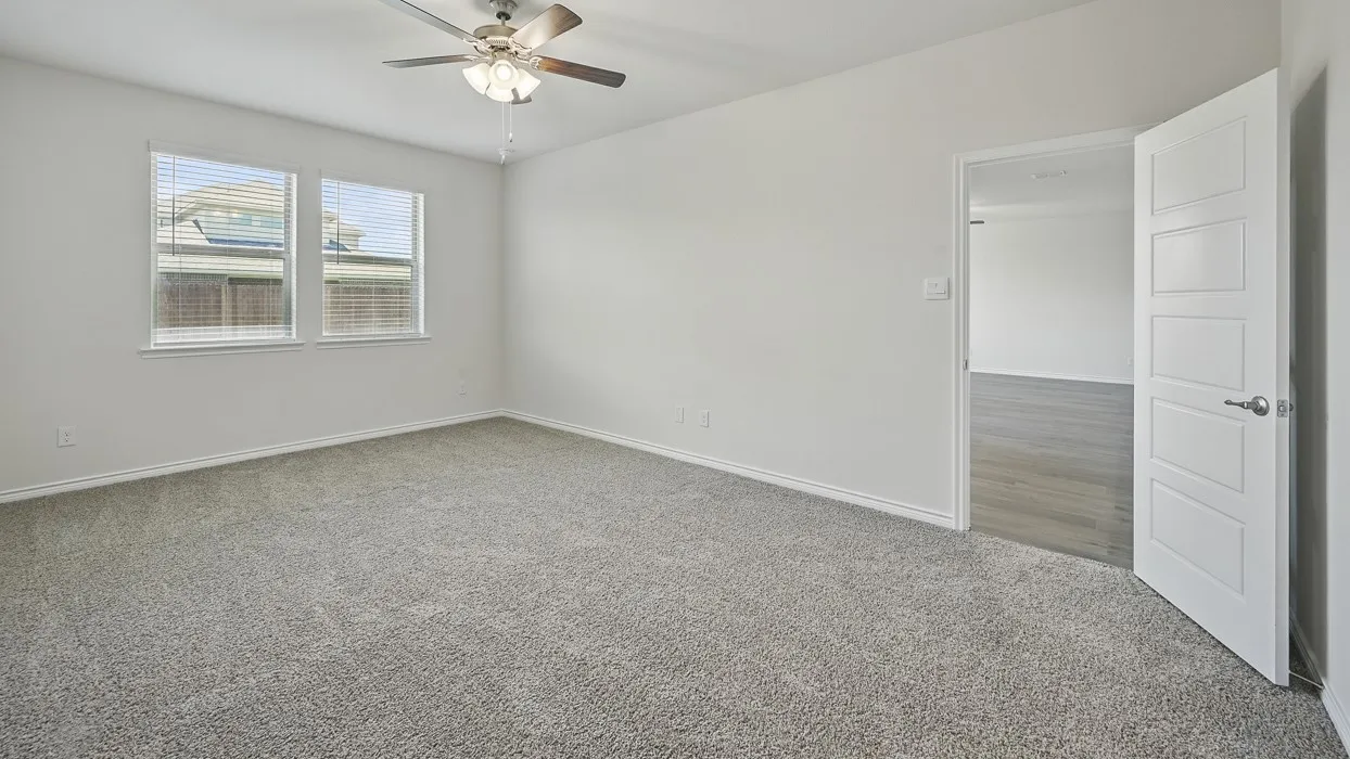Carpeted room featuring two windows with blinds, a ceiling fan with integrated lighting, and a five-panel interior door