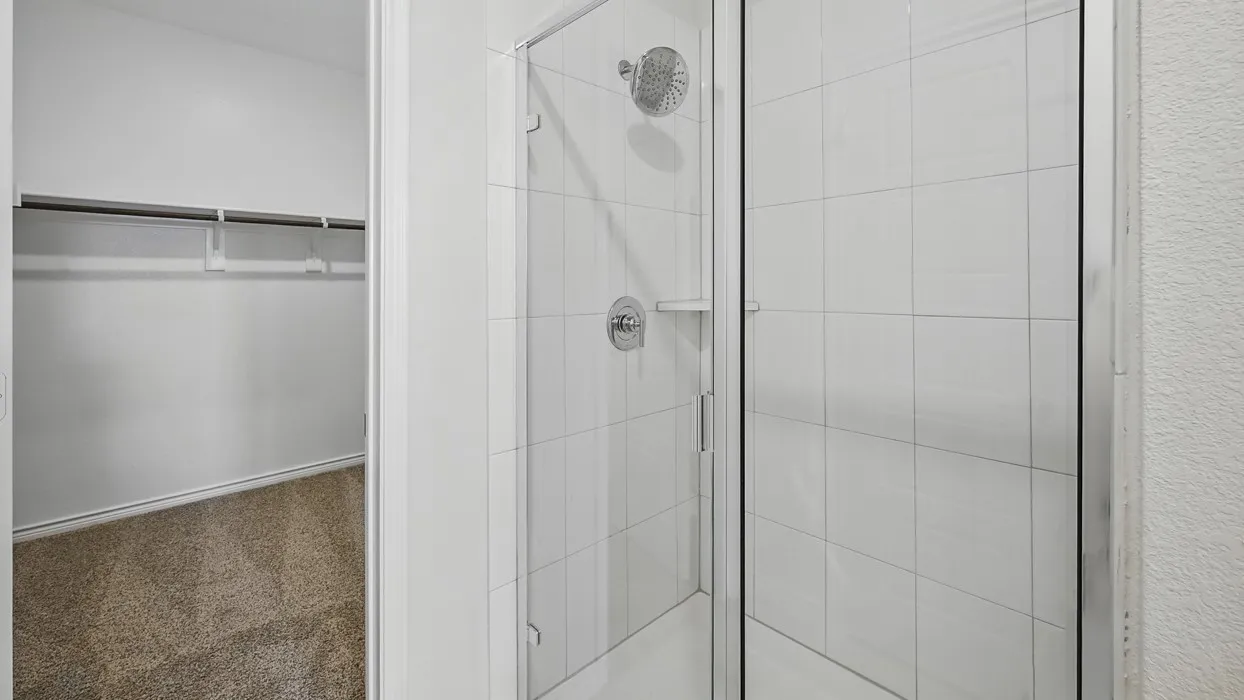 Shower enclosure with clear glass door, white rectangular tile surround, and chrome fixtures