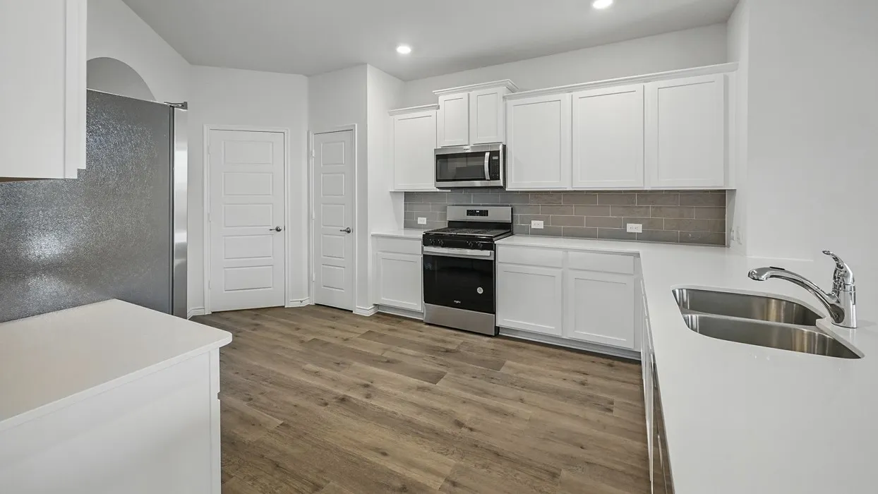 Kitchen featuring white cabinetry, light-toned countertops, wood-finish flooring, a stainless steel double-basin sink, and a gray subway tile backsplash