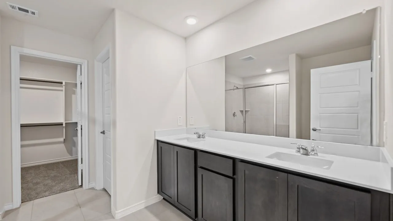 Double vanity with integrated sinks, white countertops, and dark wood-finish cabinetry