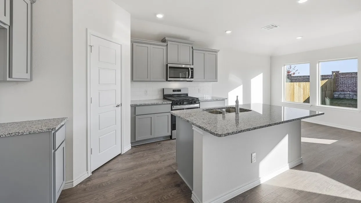 Kitchen featuring a central island with a double basin sink, gray cabinetry, stainless steel appliances, and wood-finish flooring