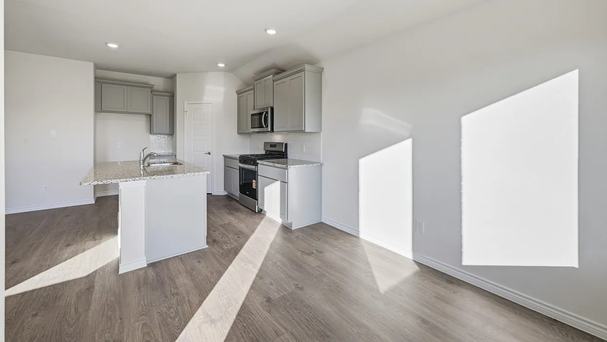 Open-concept kitchen and living area featuring wood-finish flooring, recessed lighting, a kitchen island with an undermount sink, granite countertops, and stainless steel appliances