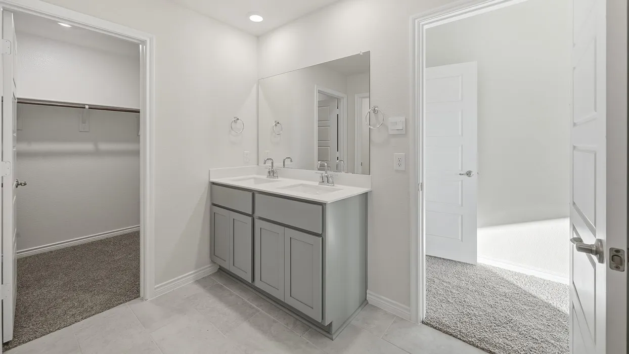 Bathroom featuring a double vanity with stone-finish countertop, dual sinks, and light gray cabinetry