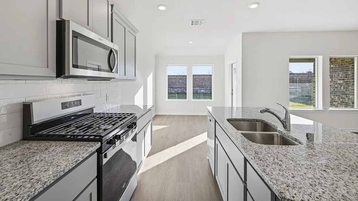 Kitchen featuring granite countertops, stainless steel appliances, grey cabinetry, a white subway tile backsplash, and wood-finish flooring