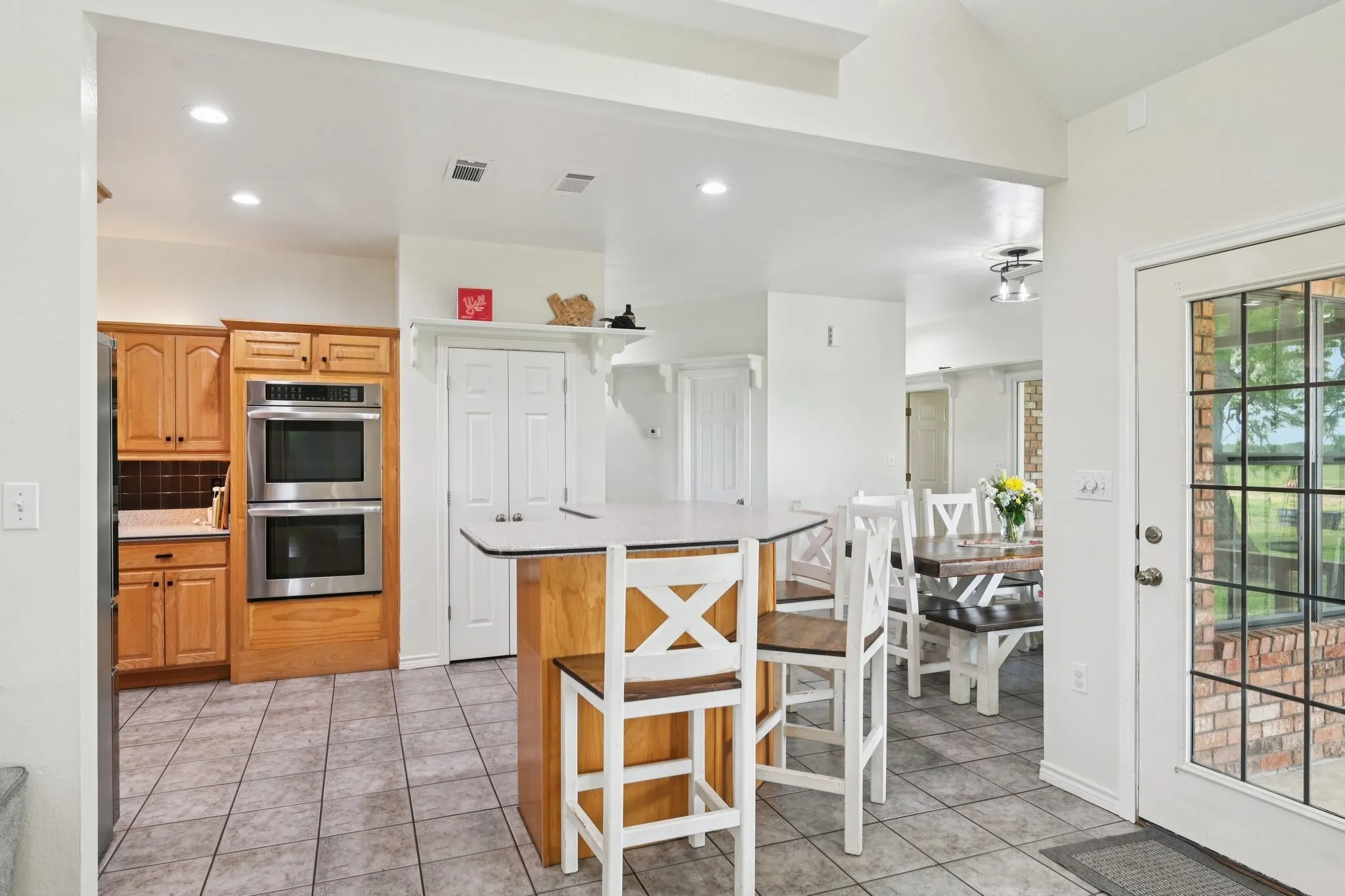 View of the Kitchen with Double Stainless Steel Ovens, Eat In Kitchen Area, Dining Area.  All with an abundance of natural light