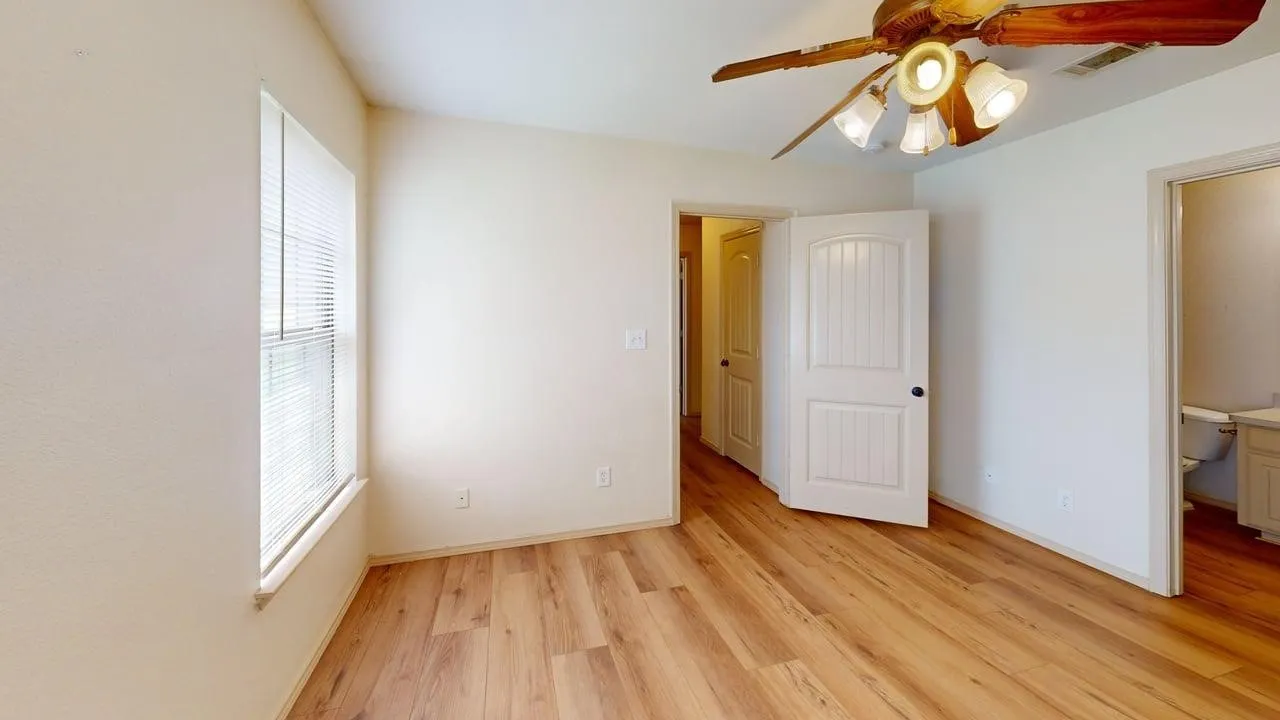 Interior room featuring wood-finish flooring and a ceiling fan with integrated lighting