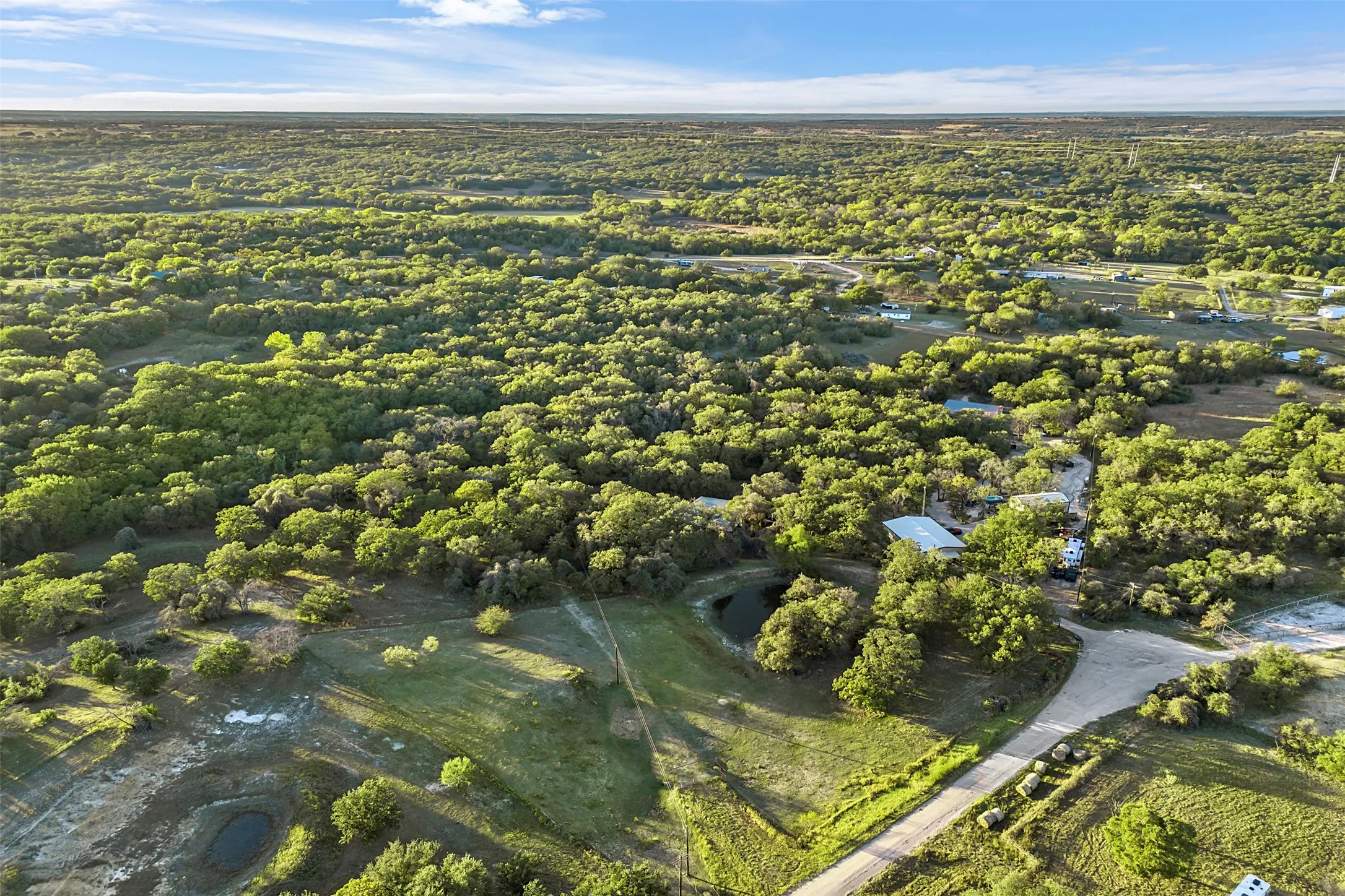 Expansive land parcel featuring dense tree coverage, open grassy areas, and visible water features
