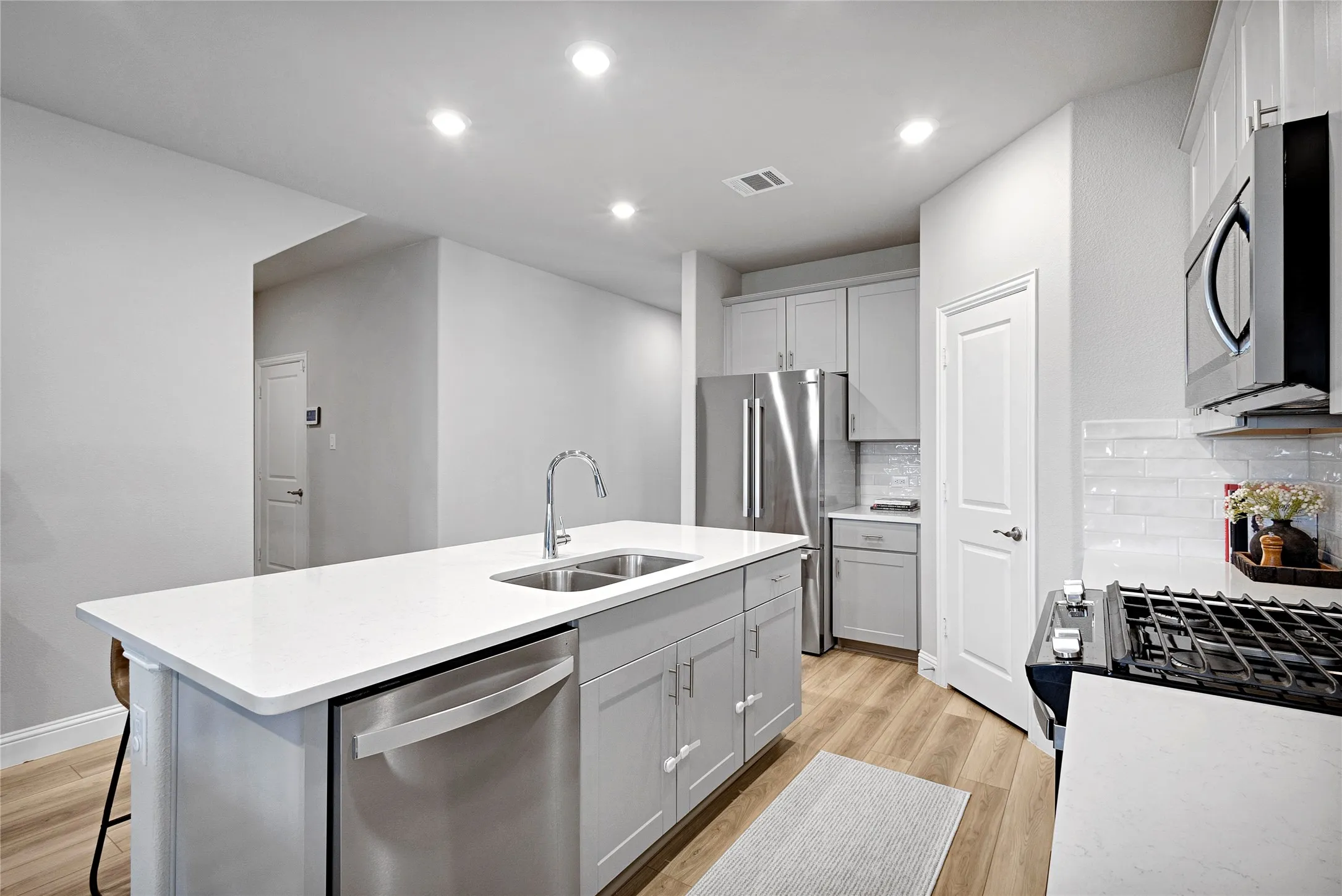 Spacious kitchen with white cabinets and quartz coutertops.