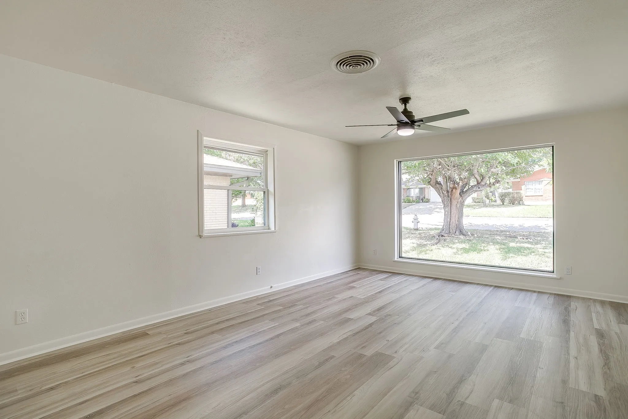 Spacious room with wood-finish flooring and a contemporary ceiling fan