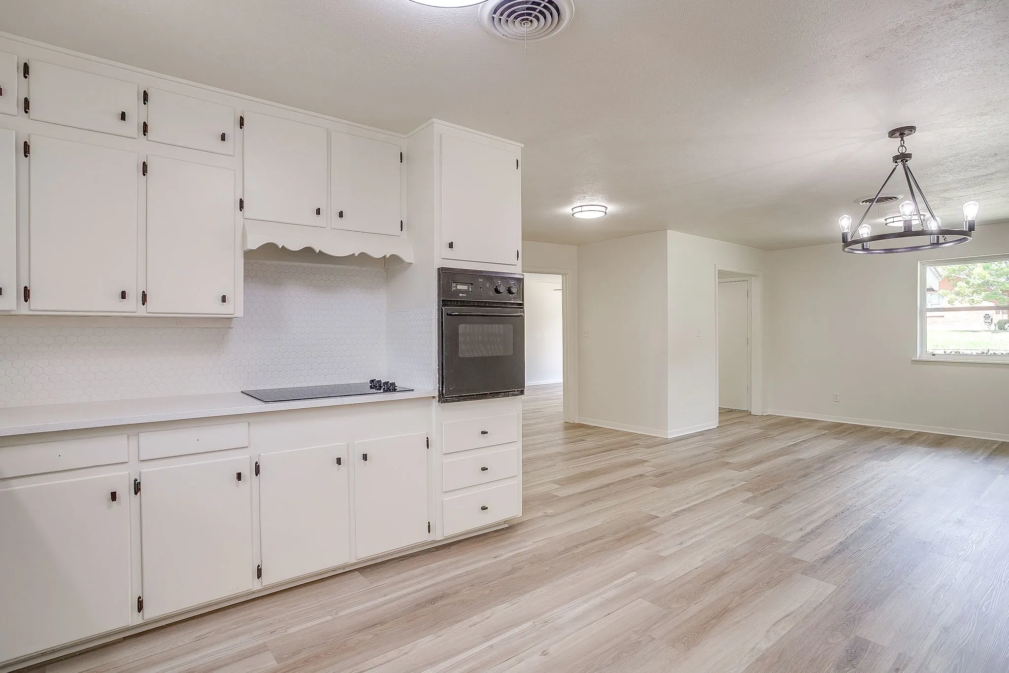 Bright kitchen featuring extensive white cabinetry, a built-in wall oven, and a cooktop