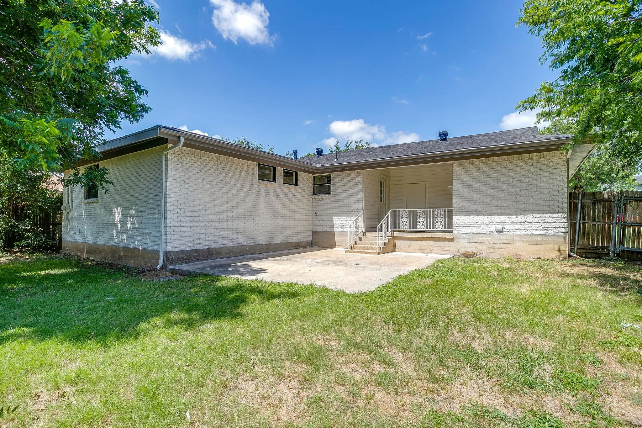 Rear exterior featuring white brick siding and a concrete patio