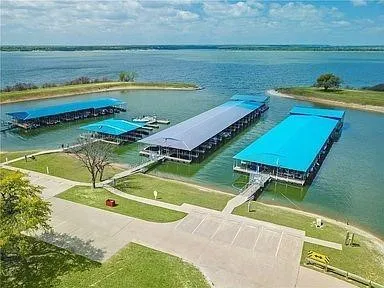 Expansive lakefront property featuring multiple covered boat docks and a concrete parking area