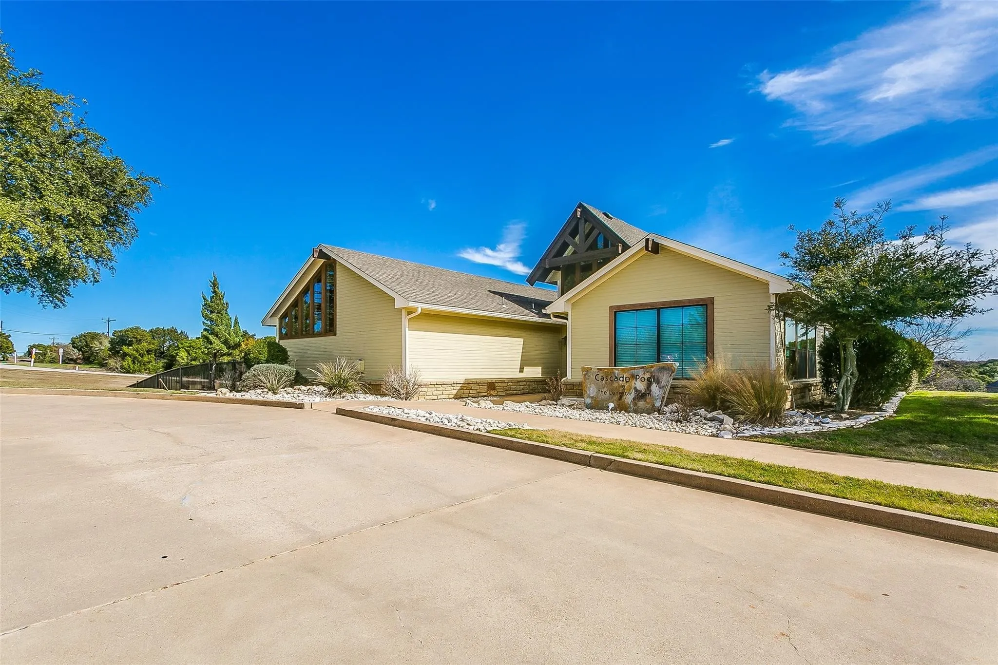 Contemporary-style property with light yellow siding, a prominent gabled roofline, and an exposed timber frame accent