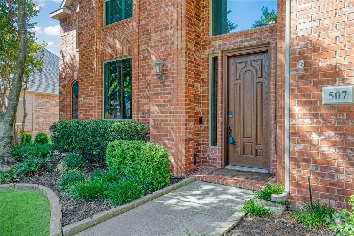 Brick facade featuring a carved wood entry door, an overhead transom window, and a sidelight