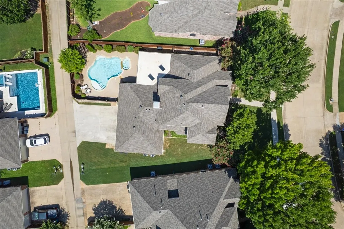Expansive property featuring a multi-gabled roofline, concrete driveway, and a private swimming pool with surrounding patio