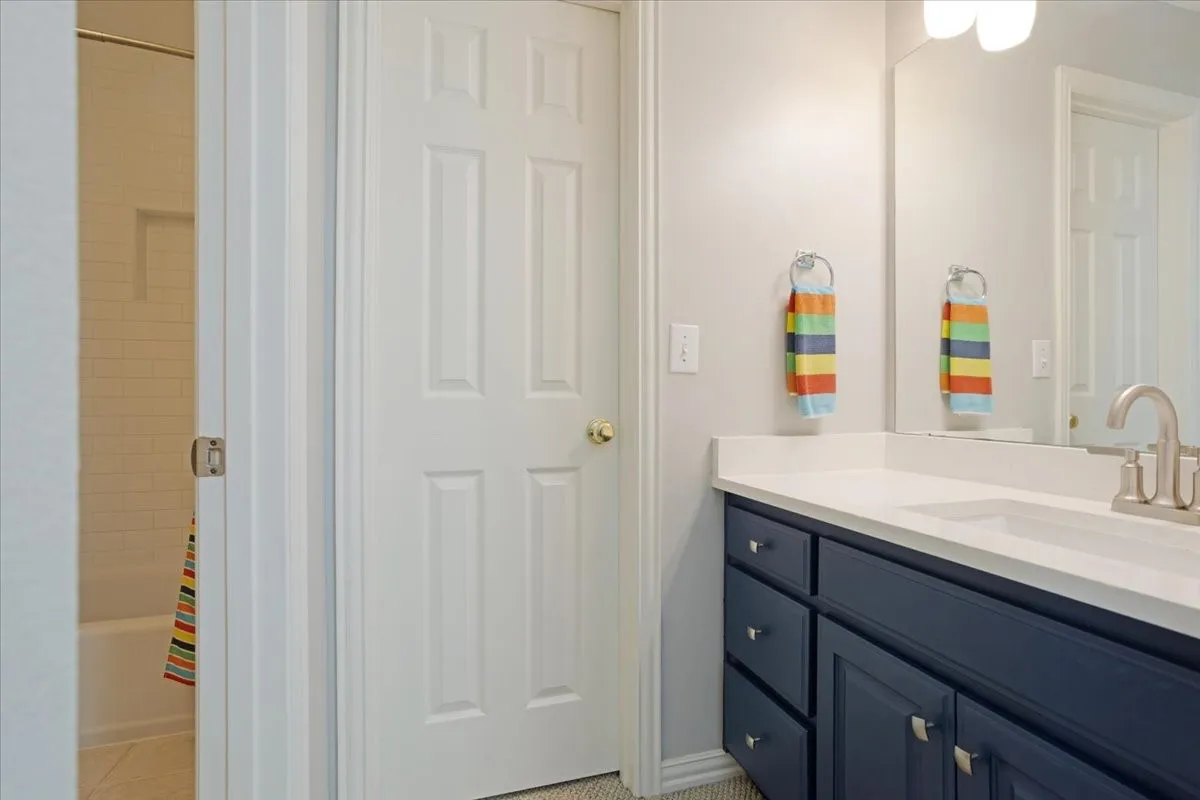 Bathroom vanity featuring a white countertop, undermount sink, and matte silver faucet