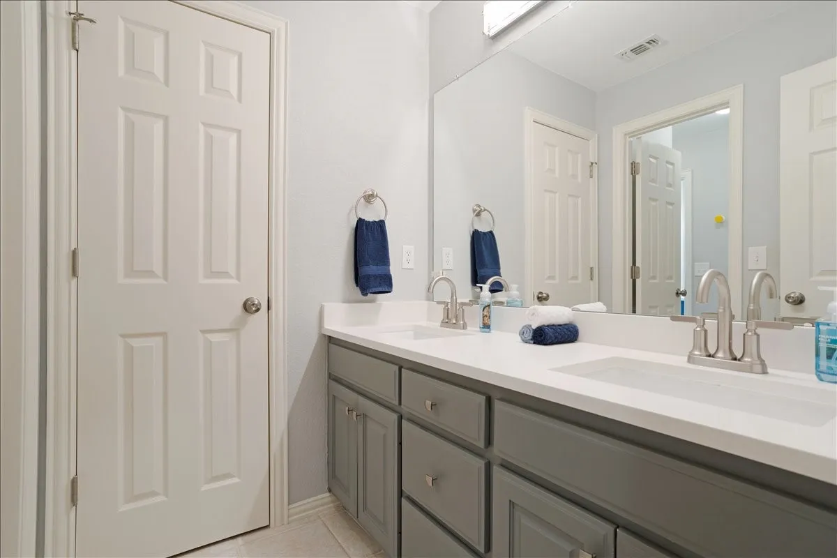 Dual vanity featuring grey shaker-style cabinetry, a white countertop, and brushed nickel fixtures