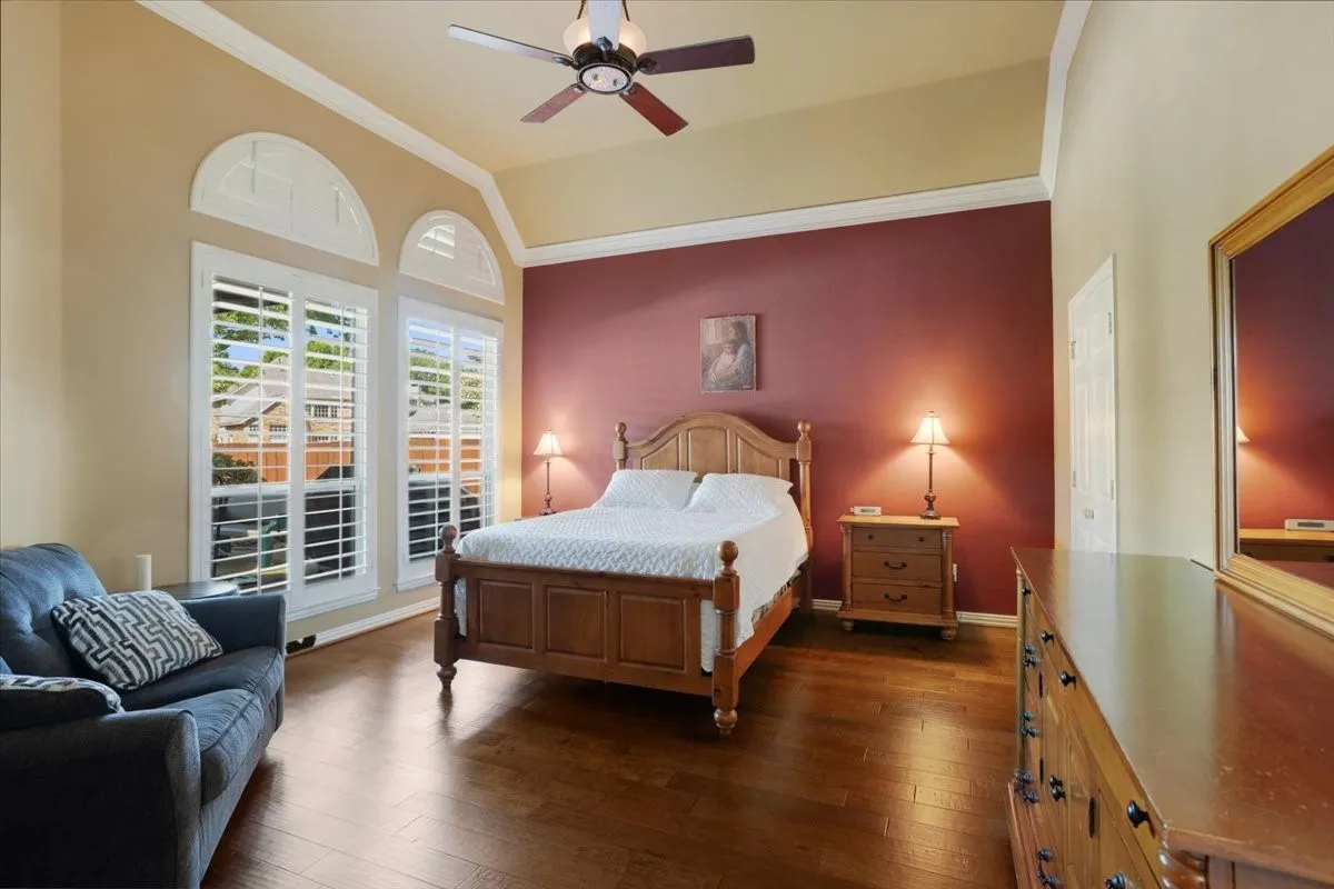 Hardwood flooring throughout featuring arched windows with plantation shutters
