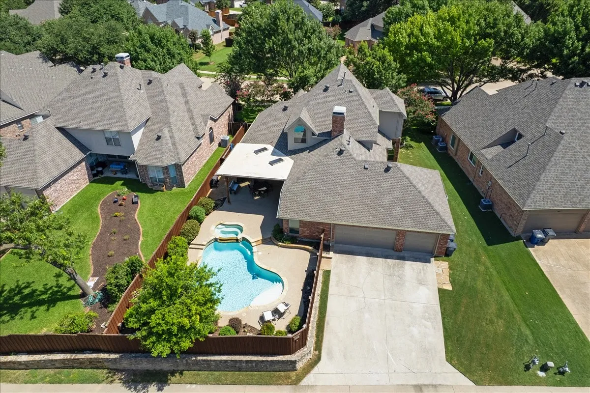 Expansive backyard featuring a freeform swimming pool with integrated spa, a concrete pool deck, and a covered patio structure