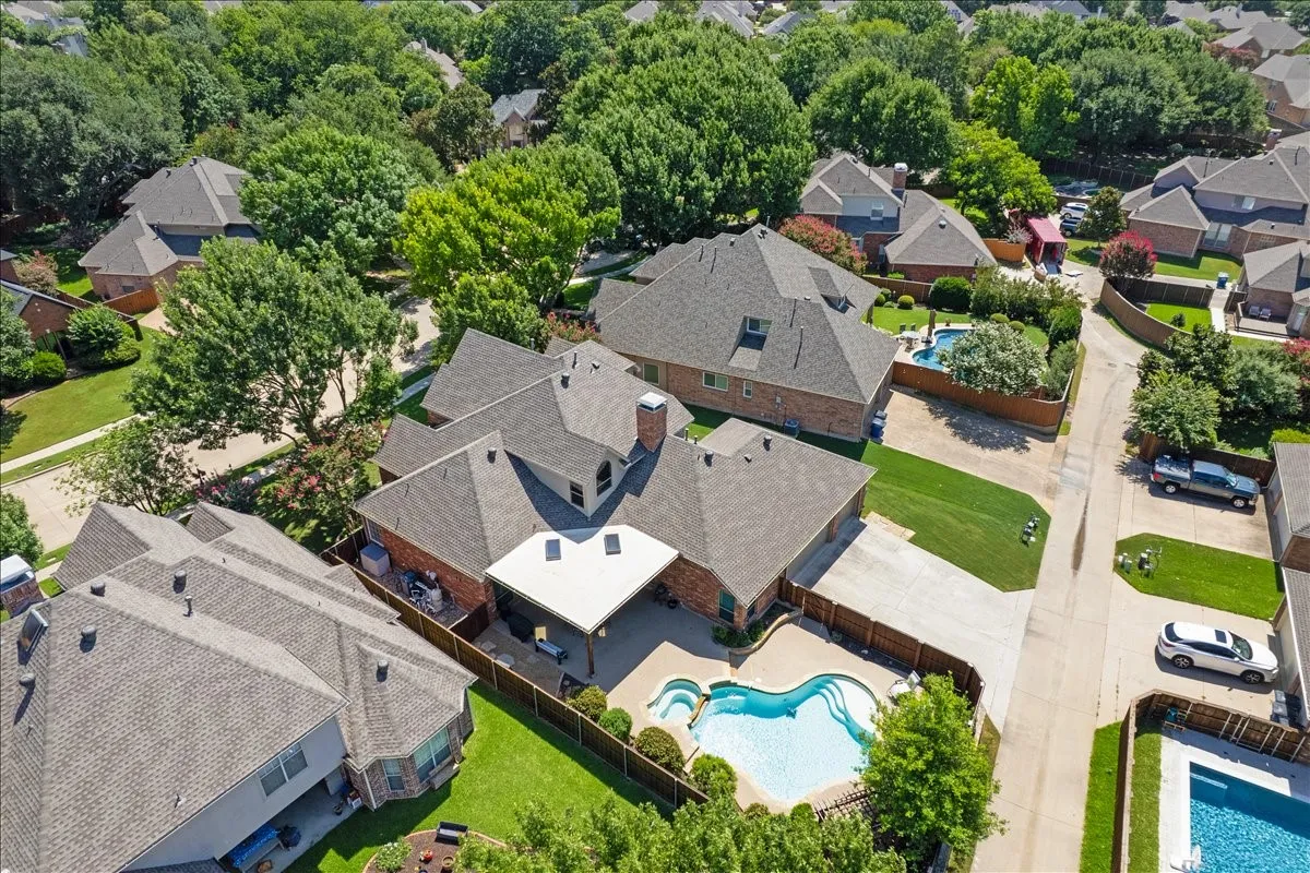 Aerial view highlighting a residential property with a multi-level roofline, a private swimming pool, and a covered patio structure