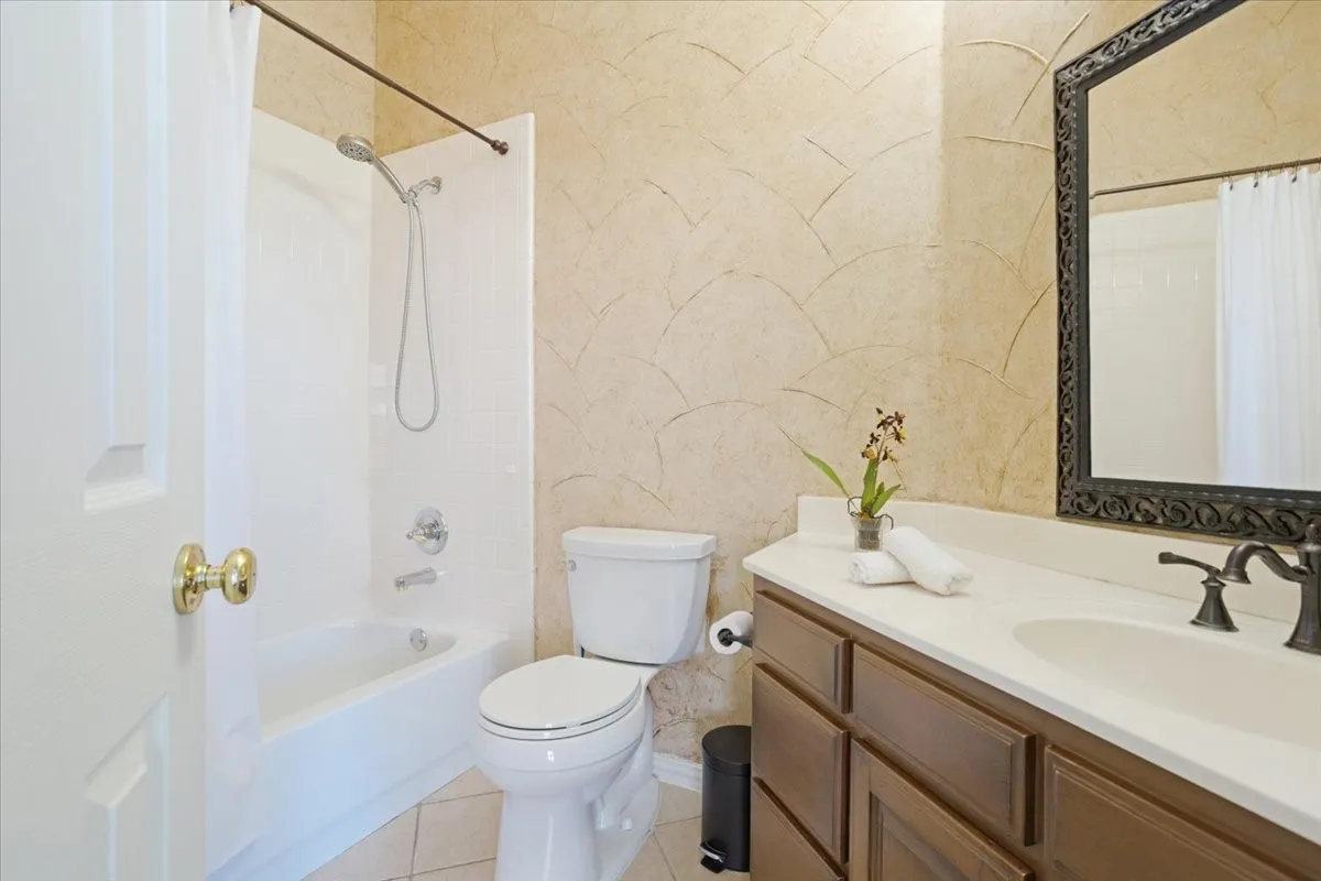 Bathroom featuring a single vanity with a white countertop, dark wood-finish cabinetry, and an ornate framed mirror