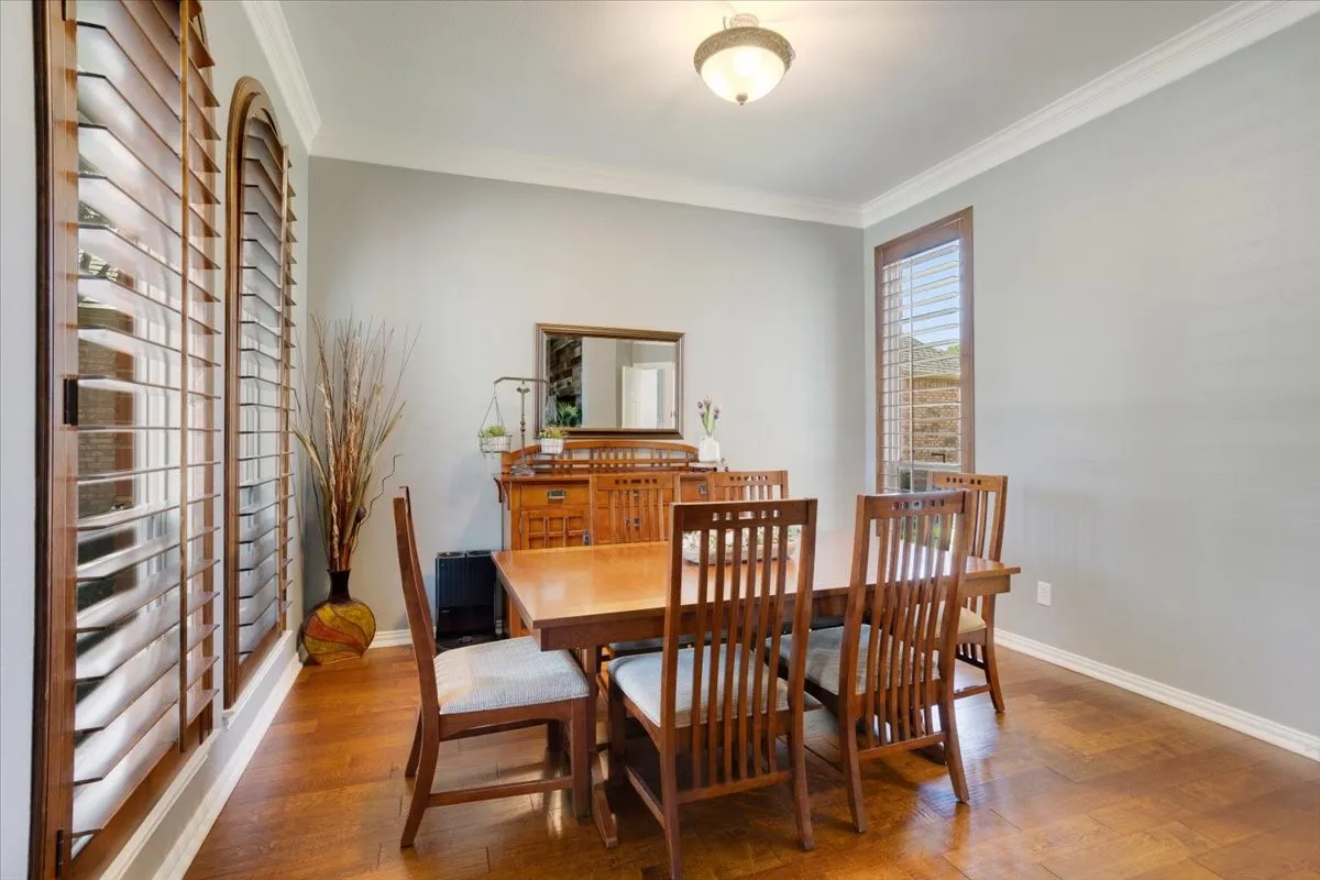 Formal dining space featuring wood-finish flooring, plantation shutters, and a wood-frame window