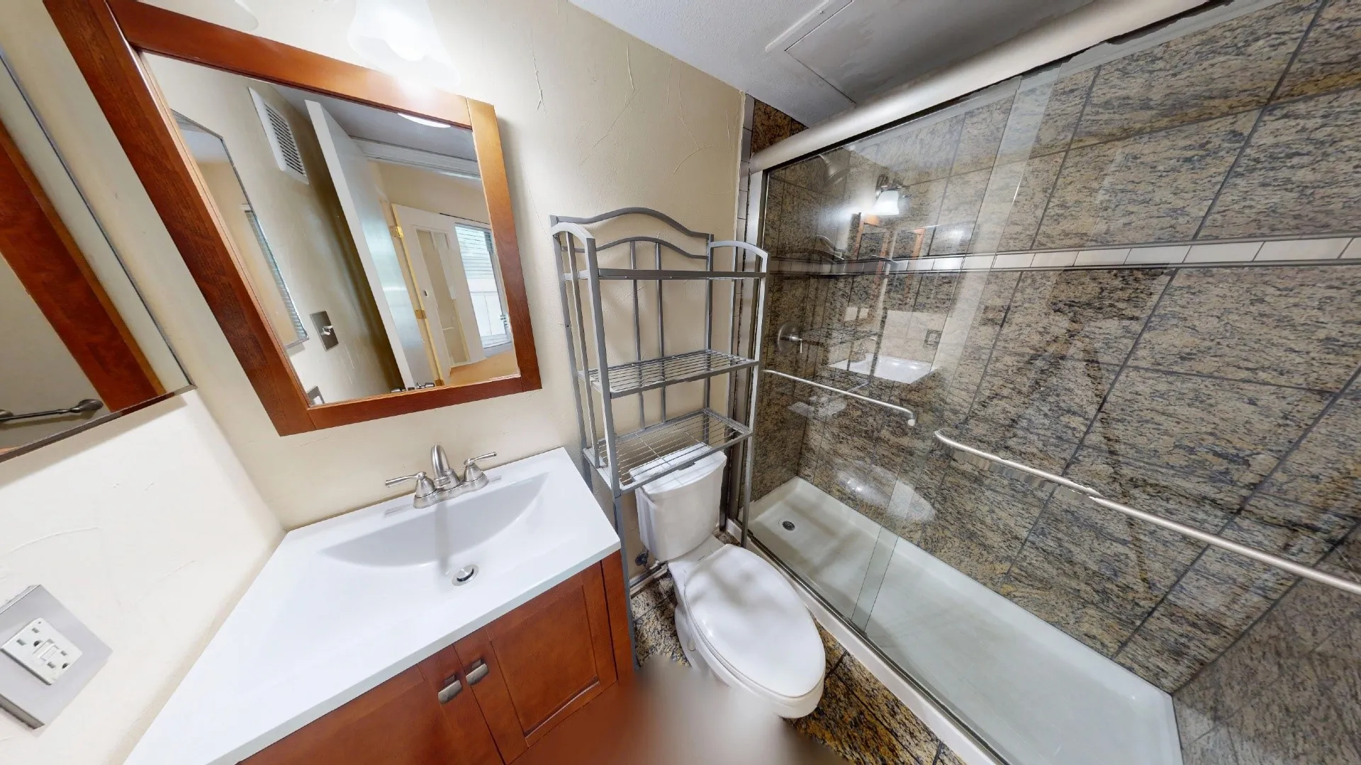 Bathroom featuring a corner vanity with a white sink, wood-finish cabinetry, and a framed mirror