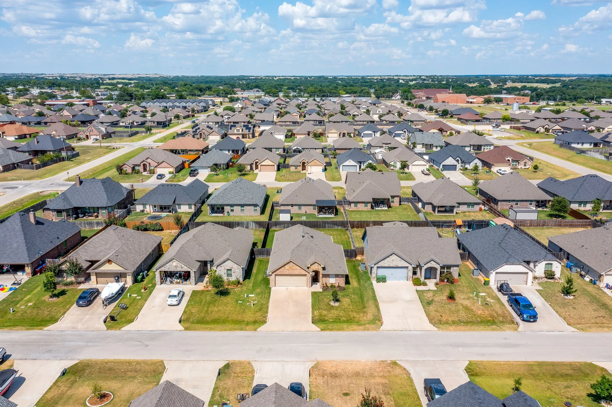 Suburban residential area featuring single-story homes with attached garages, paved driveways, and individual fenced backyards