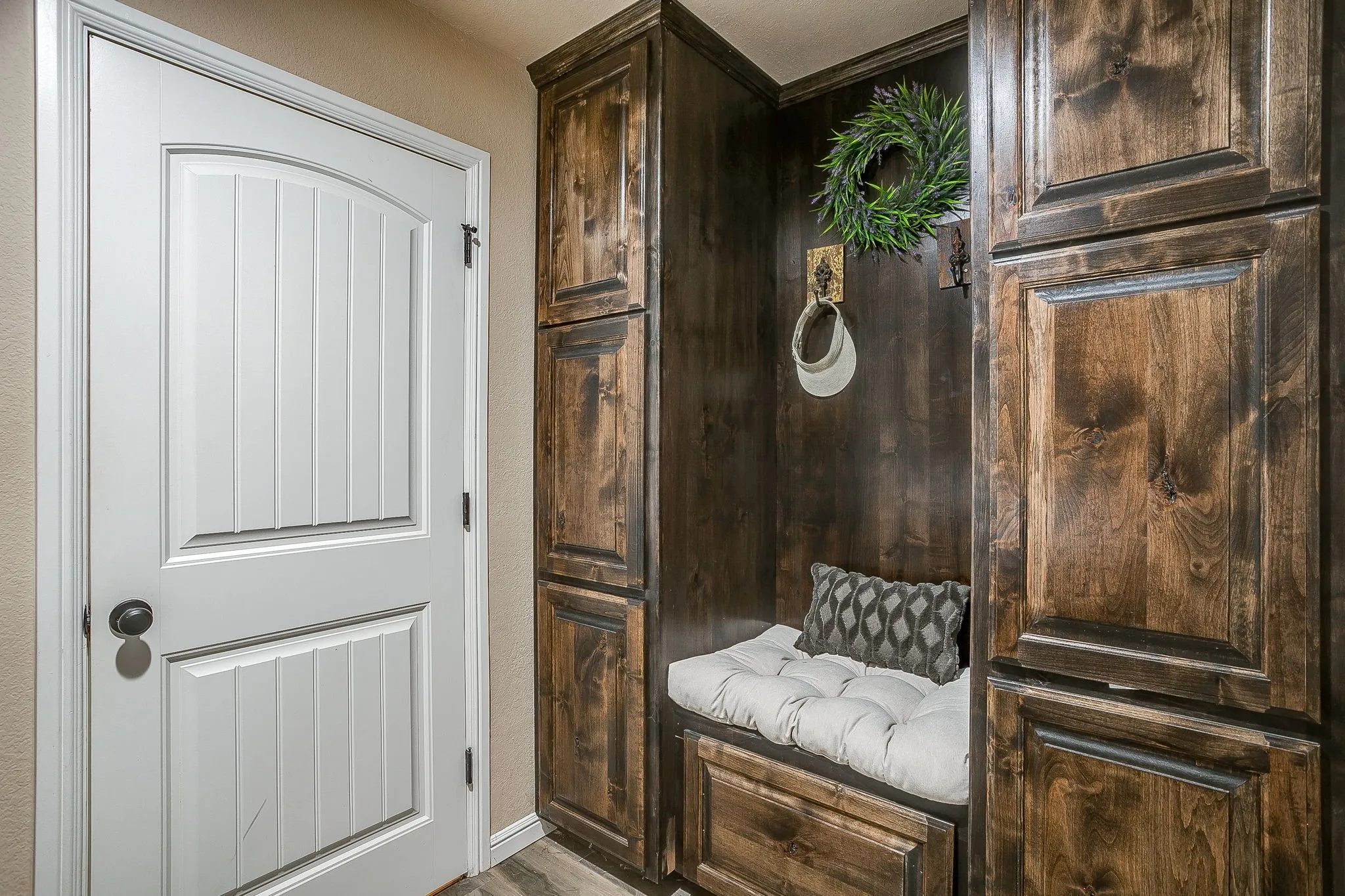 Entryway featuring a white paneled door with an arched top, dark wood-finish cabinetry, a built-in bench with storage, and integrated wall hooks