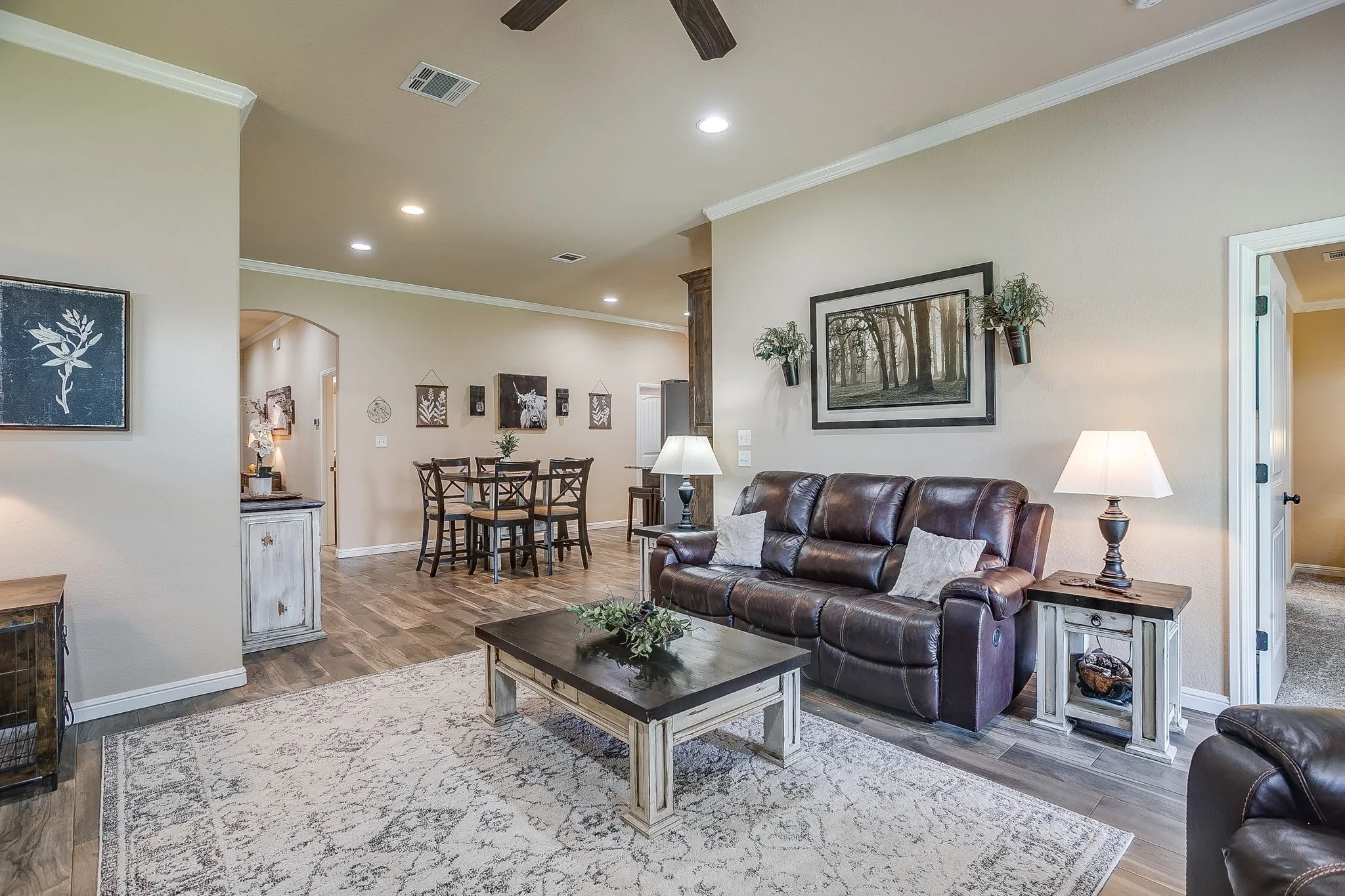 Living room featuring a stone-clad fireplace with a wood mantel, vaulted ceiling, and wood-finish flooring
