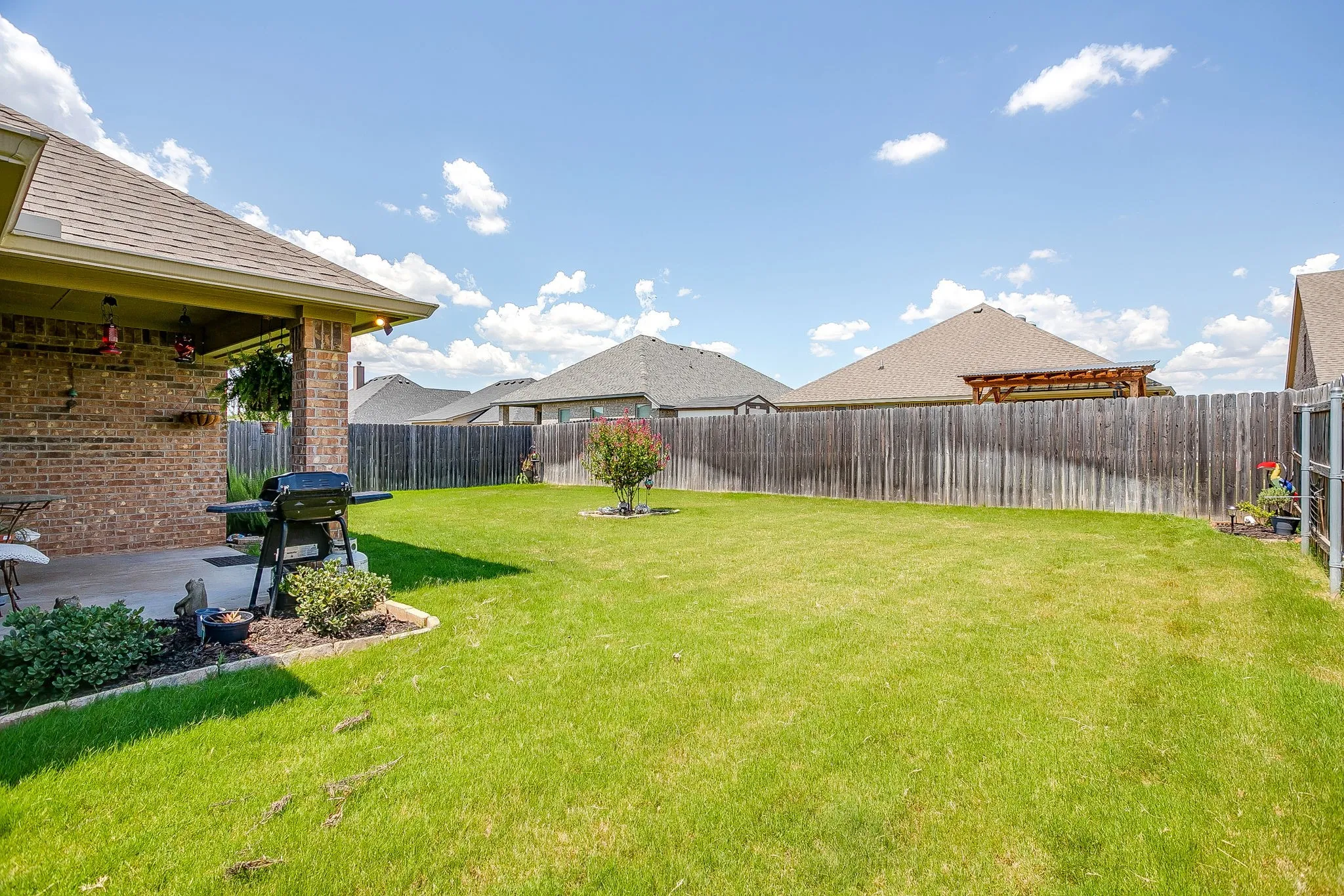 Expansive grassy yard area with a wood privacy fence
