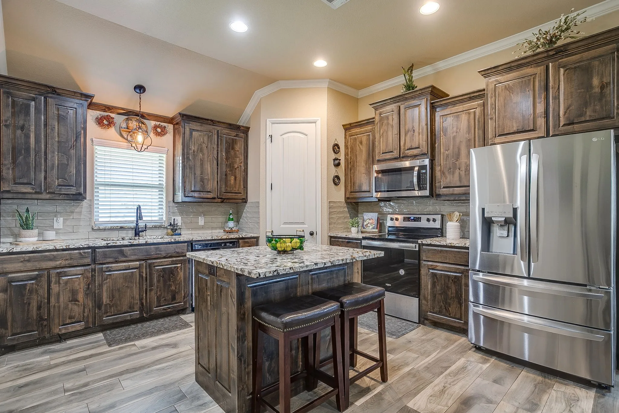 Kitchen featuring granite countertops, wood cabinetry, stainless steel range, built-in microwave, and subway tile backsplash