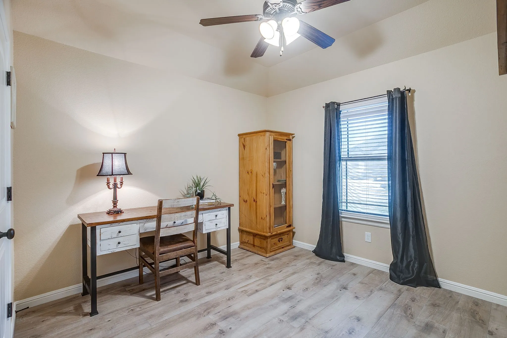 Room featuring light-toned walls, wood-finish flooring, and a ceiling fan with integrated lighting