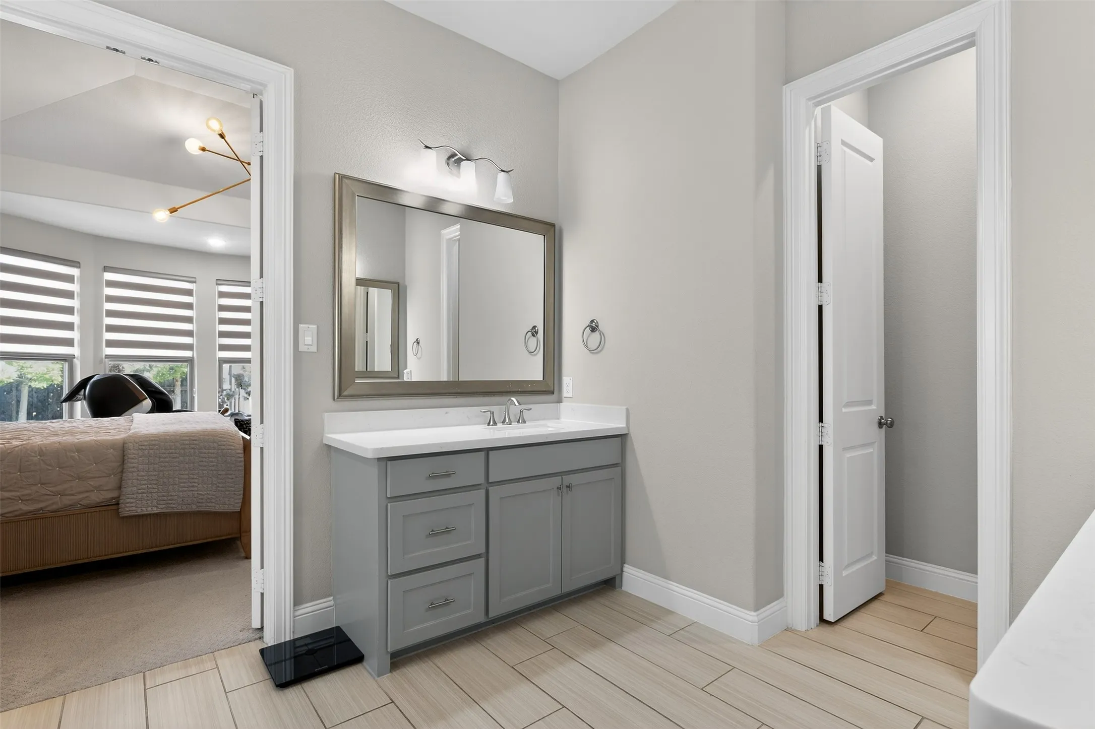 Bathroom vanity featuring a light gray cabinet with brushed nickel hardware, a white countertop, and a framed wall mirror