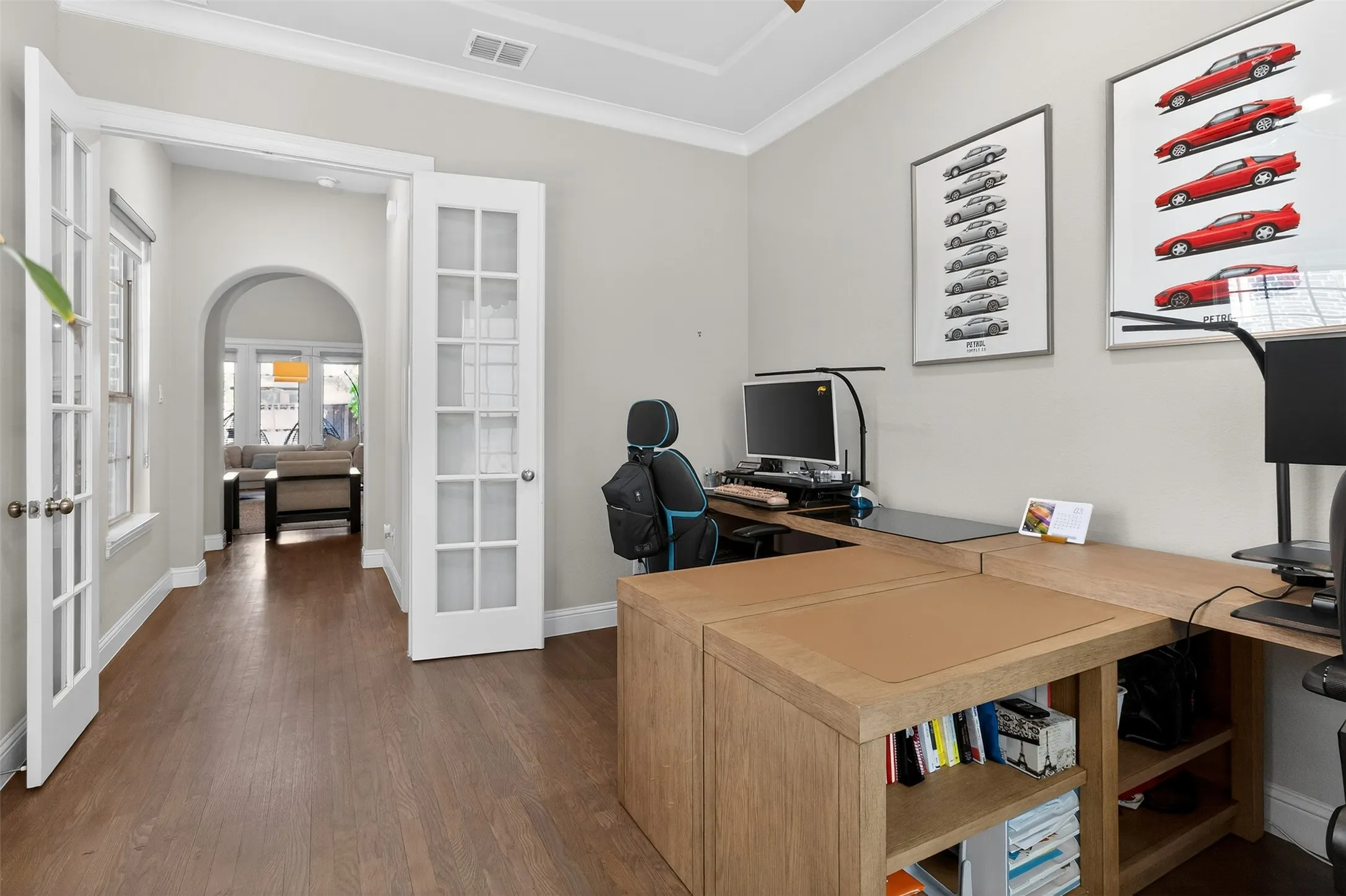 Office space featuring wood-finish flooring, light gray walls, white crown molding, and white baseboards