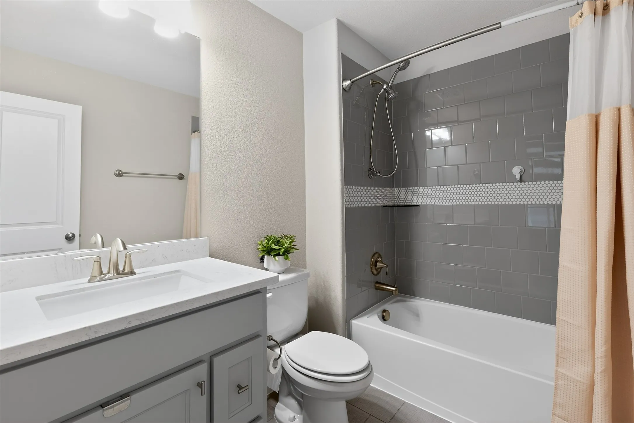 Bathroom featuring a built-in tub with gray subway tile surround and a penny tile accent strip