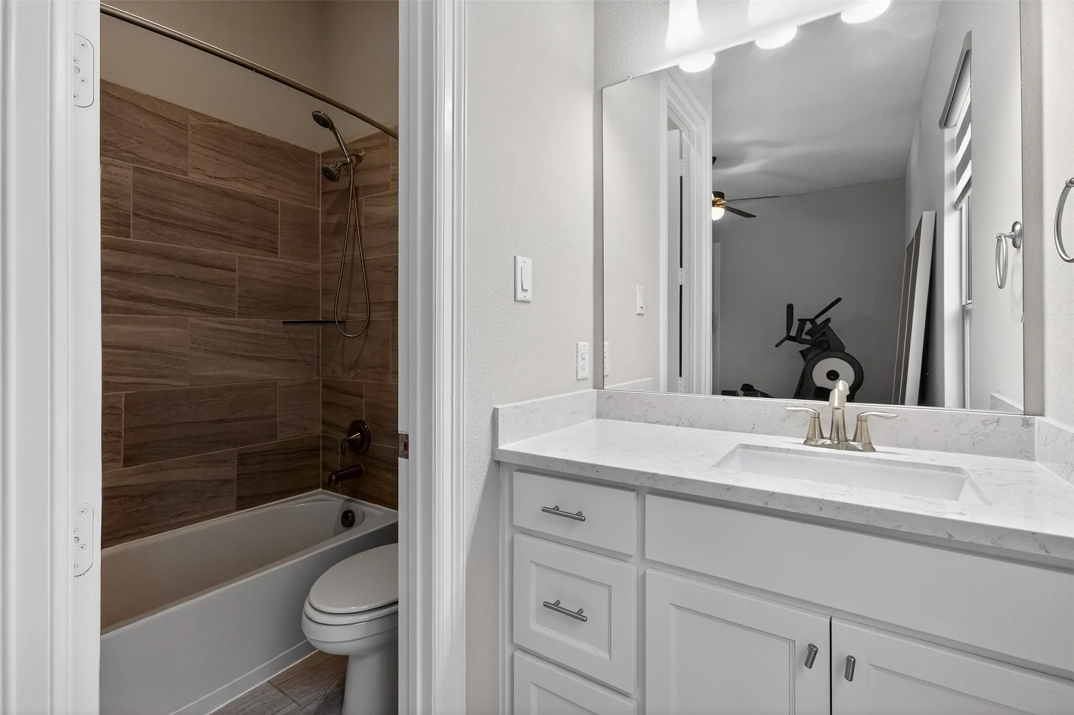 Bathroom featuring a single vanity with a white countertop and undermount sink, brushed nickel faucet, and white shaker-style cabinetry with chrome pulls