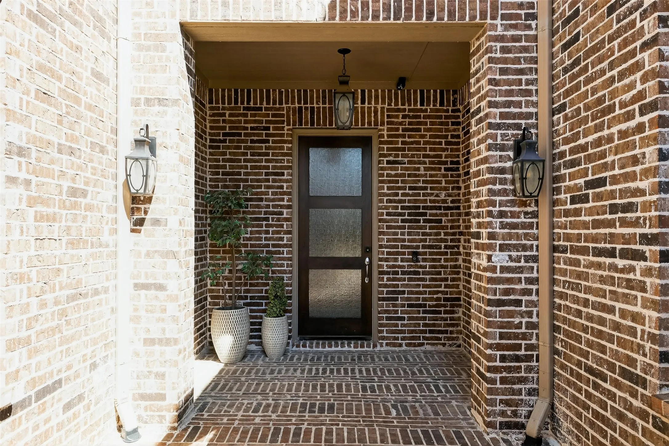Brick facade entry featuring a dark wood-finish door with frosted glass panels