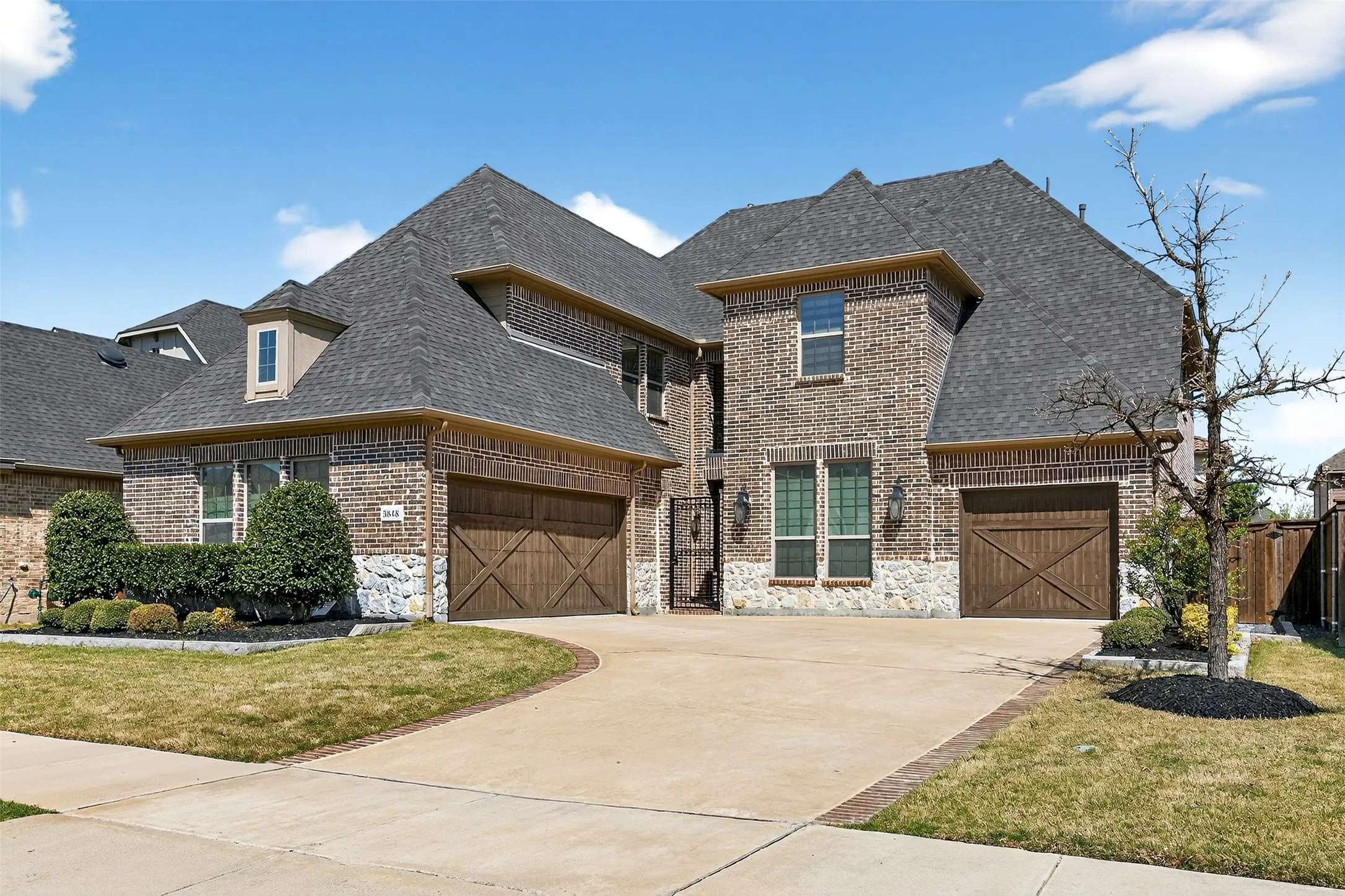 Brick exterior featuring stone accents and dark-stained wood garage doors