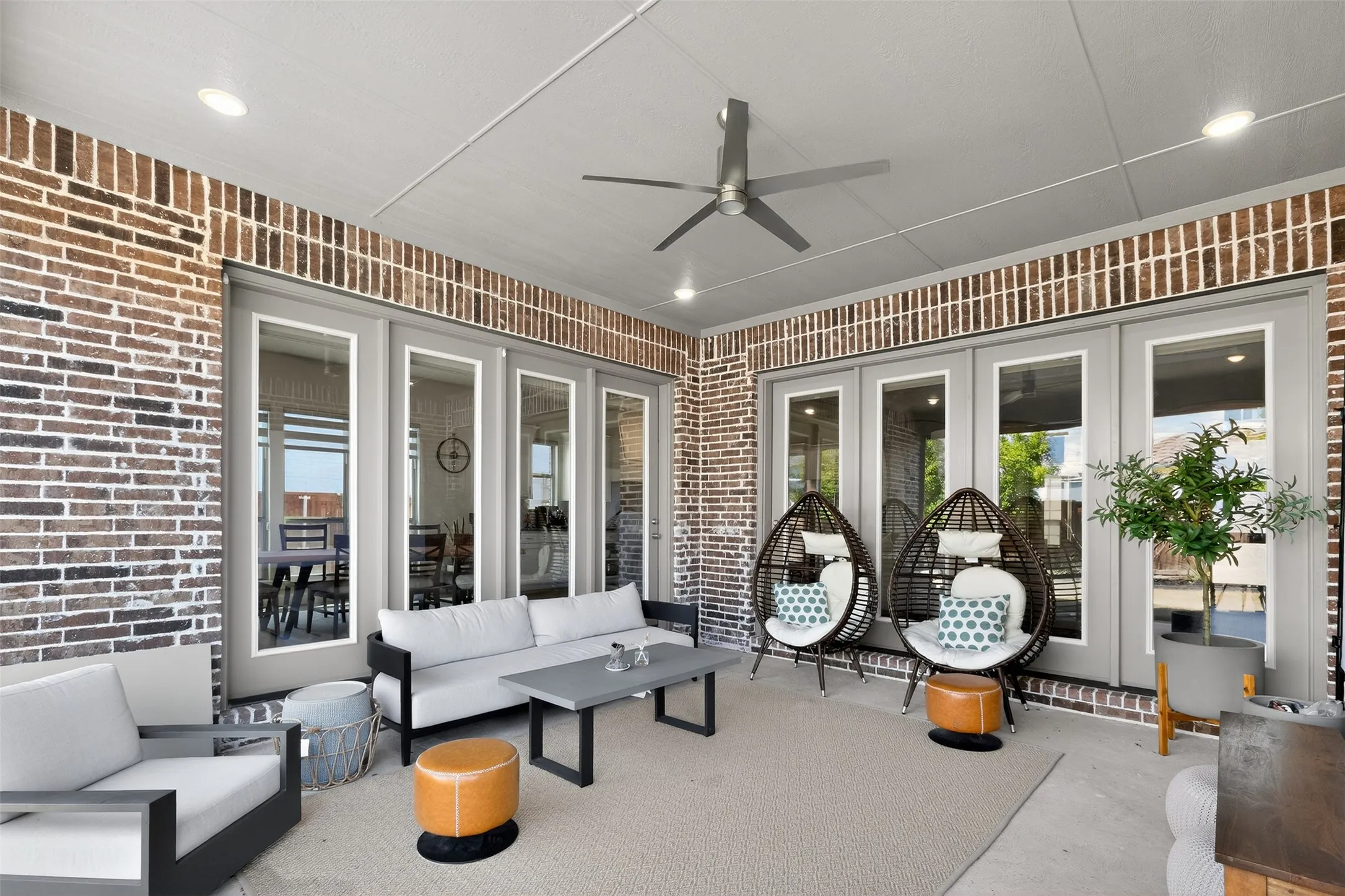 Covered patio featuring a ceiling fan, recessed lighting, and brick accent walls