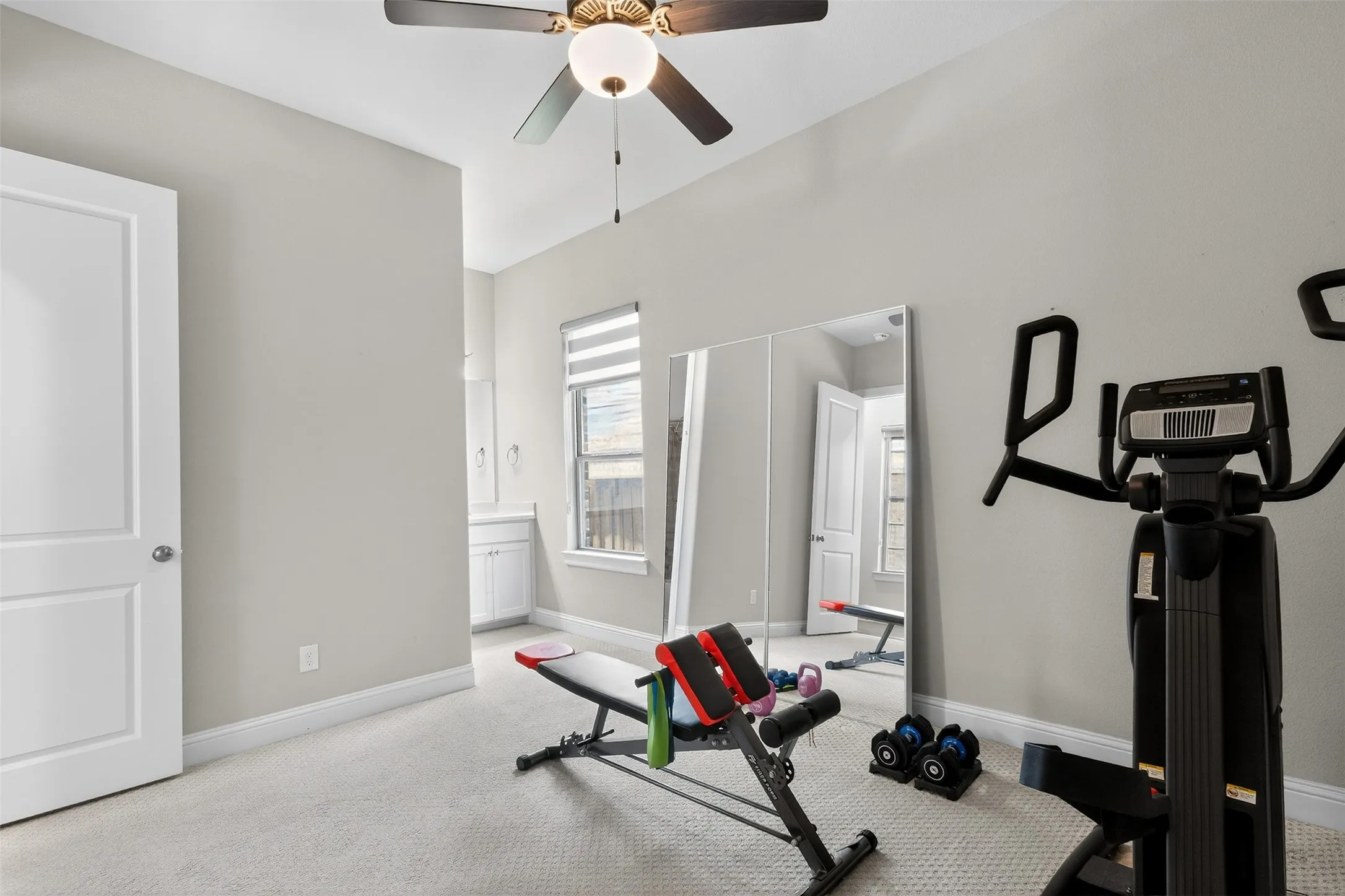 Carpeted room with a ceiling fan, white baseboards, and a window with blinds